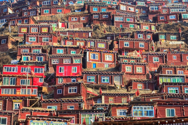 A vibrant and artistic scene of the Gamcheon Culture Village in Busan, South Korea. The colorful houses are terraced on a hillside, with winding streets and staircases. Tourists are exploring and taking photos.