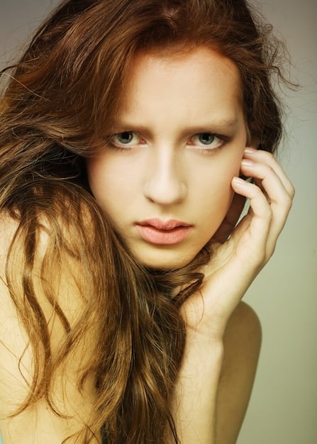 A close-up shot of a woman with long, light brown hair styled in loose, natural waves. The focus is on the texture and the slight curl at the ends. She is wearing a simple, elegant outfit, complementing the hairstyle's effortless beauty.