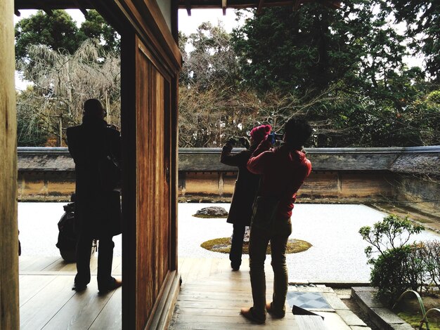 A serene image of a traditional Japanese garden, possibly used as a filming location, with fans taking photos respectfully.