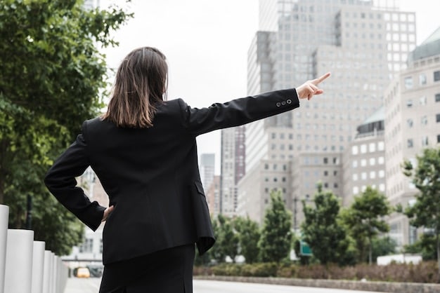 A professional Japanese woman in a sharp business suit, facing away from the camera, with sleek, straight dark hair cascading down her back, showing a subtle inward curl at the ends. The background is a modern office building interior.