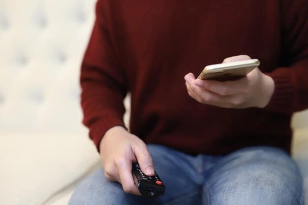 A person sitting on a couch, relaxing and using a remote control to navigate through the interface of a streaming service on their TV. The TV screen shows various Asian drama thumbnails and titles, highlighting the diverse range of content available. Focus on the ease and comfort of accessing Asian dramas via a TV streaming service.