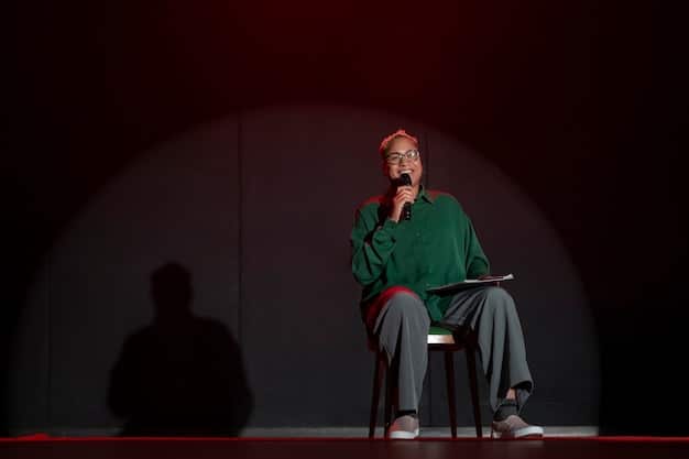 A critic sitting in a dimly lit theater, taking notes on a tablet during a live performance, with a view of the stage in the background.