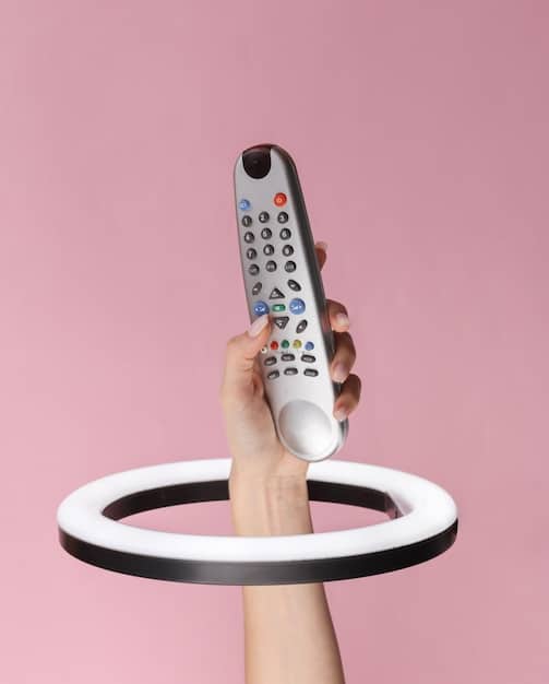 A close-up of a hand holding a smart remote control pointed at a television displaying various streaming service logos, emphasizing choice and control.